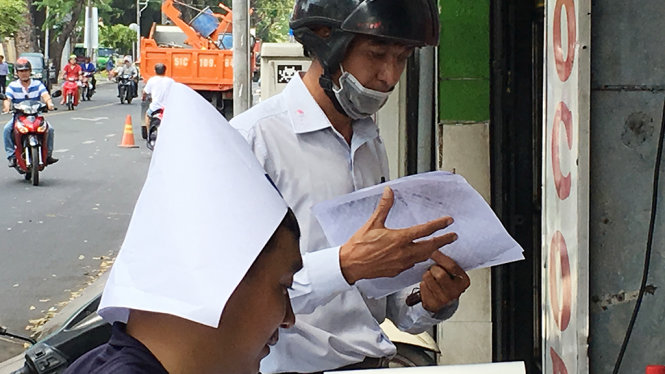 Anh thợ photocopy trên đường Nguyễn Thị Minh Khai, quận 1 TP.HCM lấy giấy sẵn có làm nón che nắng - Ảnh Tự Trung